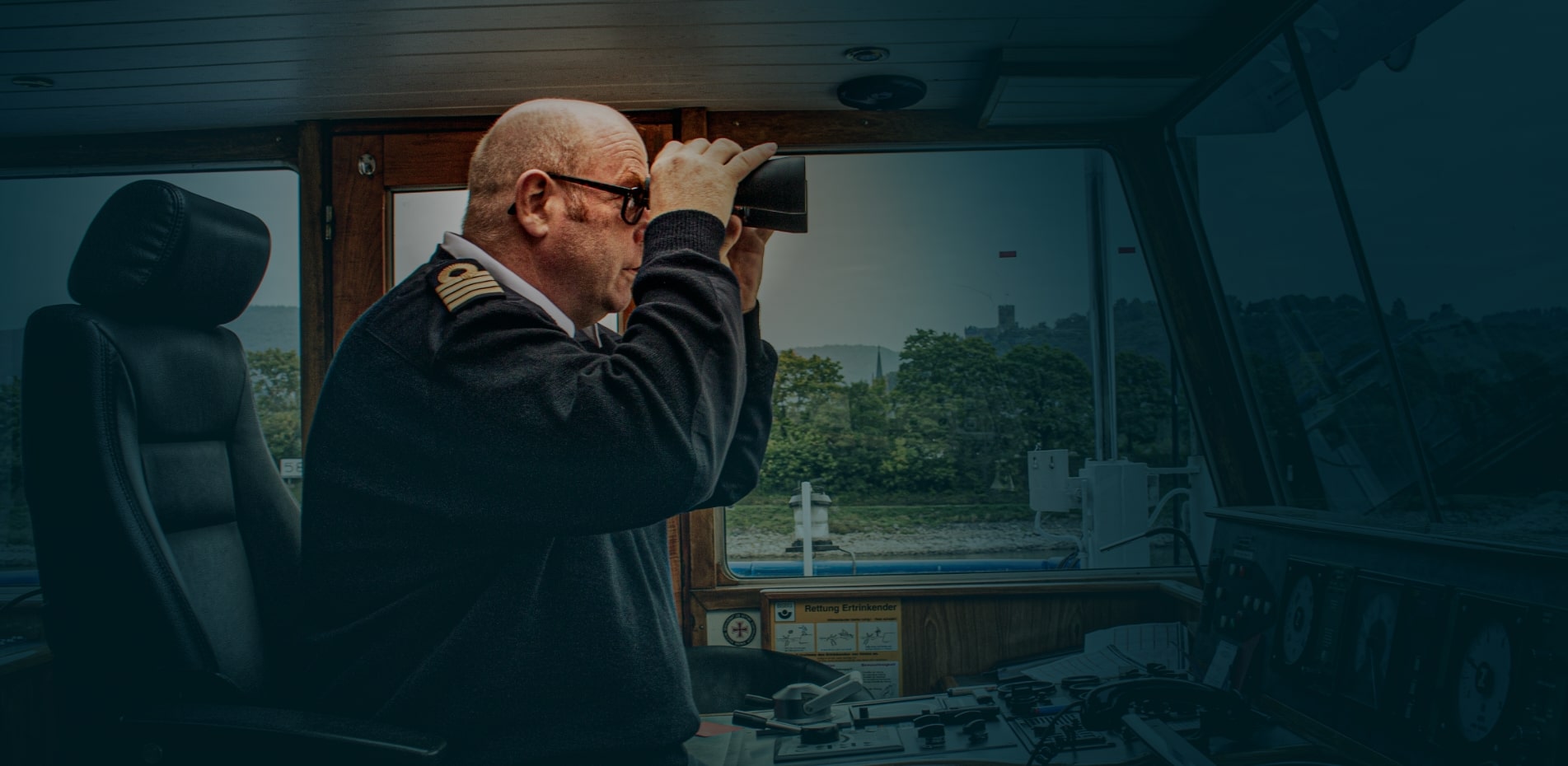 The captain looks through his binoculars in the command bridge
